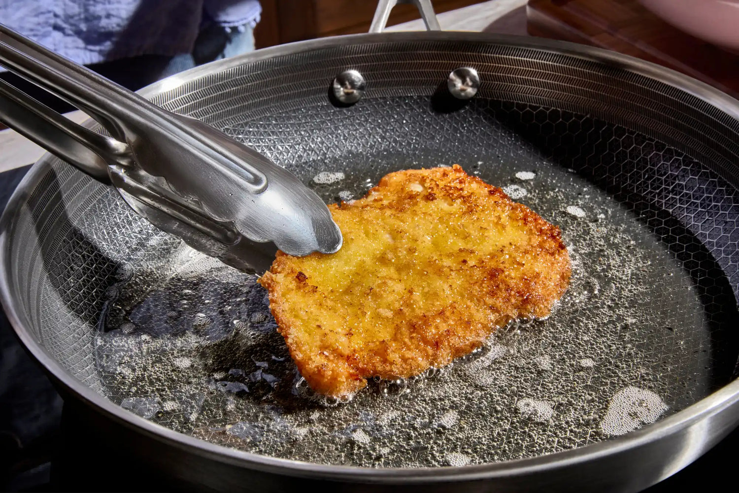 Zlatavý obalovaný řízek smažený na oleji.